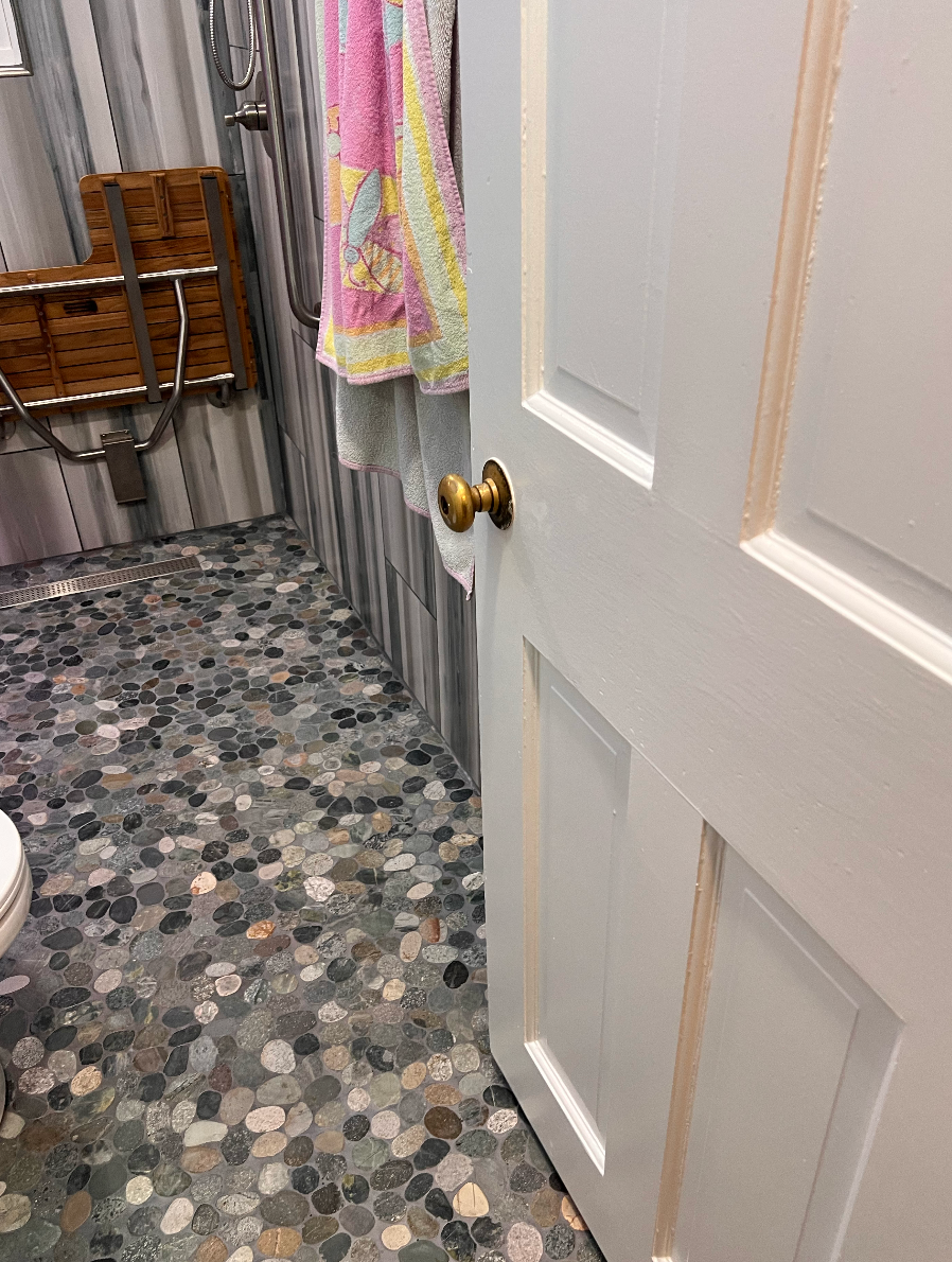 A bathroom with a tiled floor and a white door.