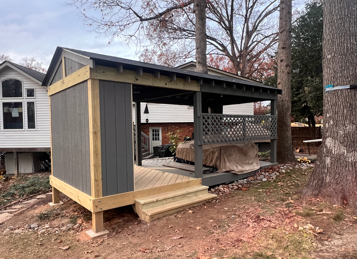 A wooden gazebo is sitting in the backyard of a house.