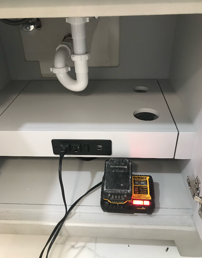 A sink underneath a cabinet with a cord plugged into it