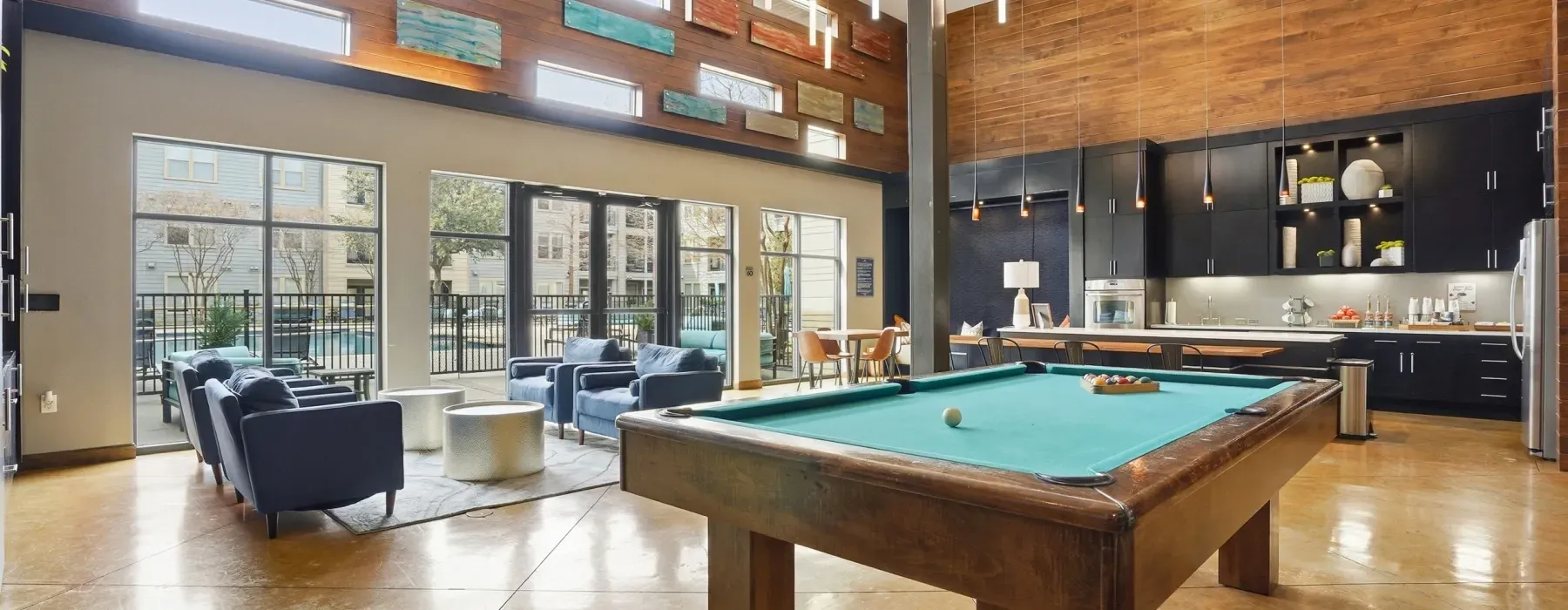 Modern loft lounge with a pool table, navy chairs, large windows, and a fireplace at Layers Galleria.