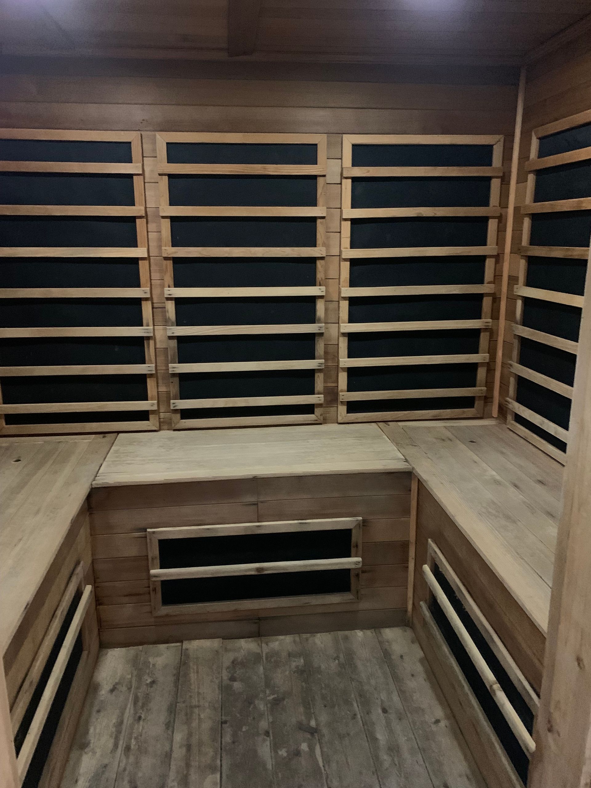 Empty wooden sauna with bench seating and shelves inside.