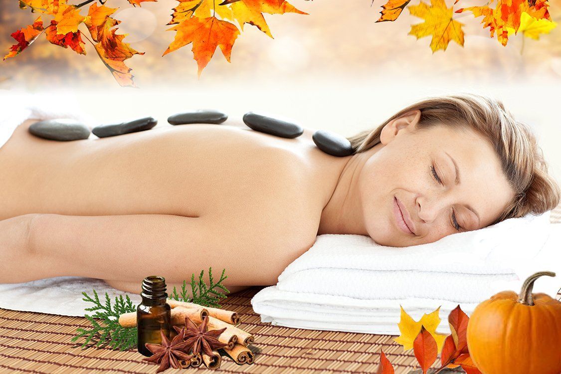Person receiving a back massage with massage stones placed on the skin
