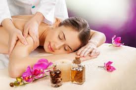 Woman receiving a spa massage with orchids and oil bottles on a towel.
