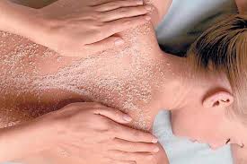 Massage therapist applying scrub to a client’s back and shoulders