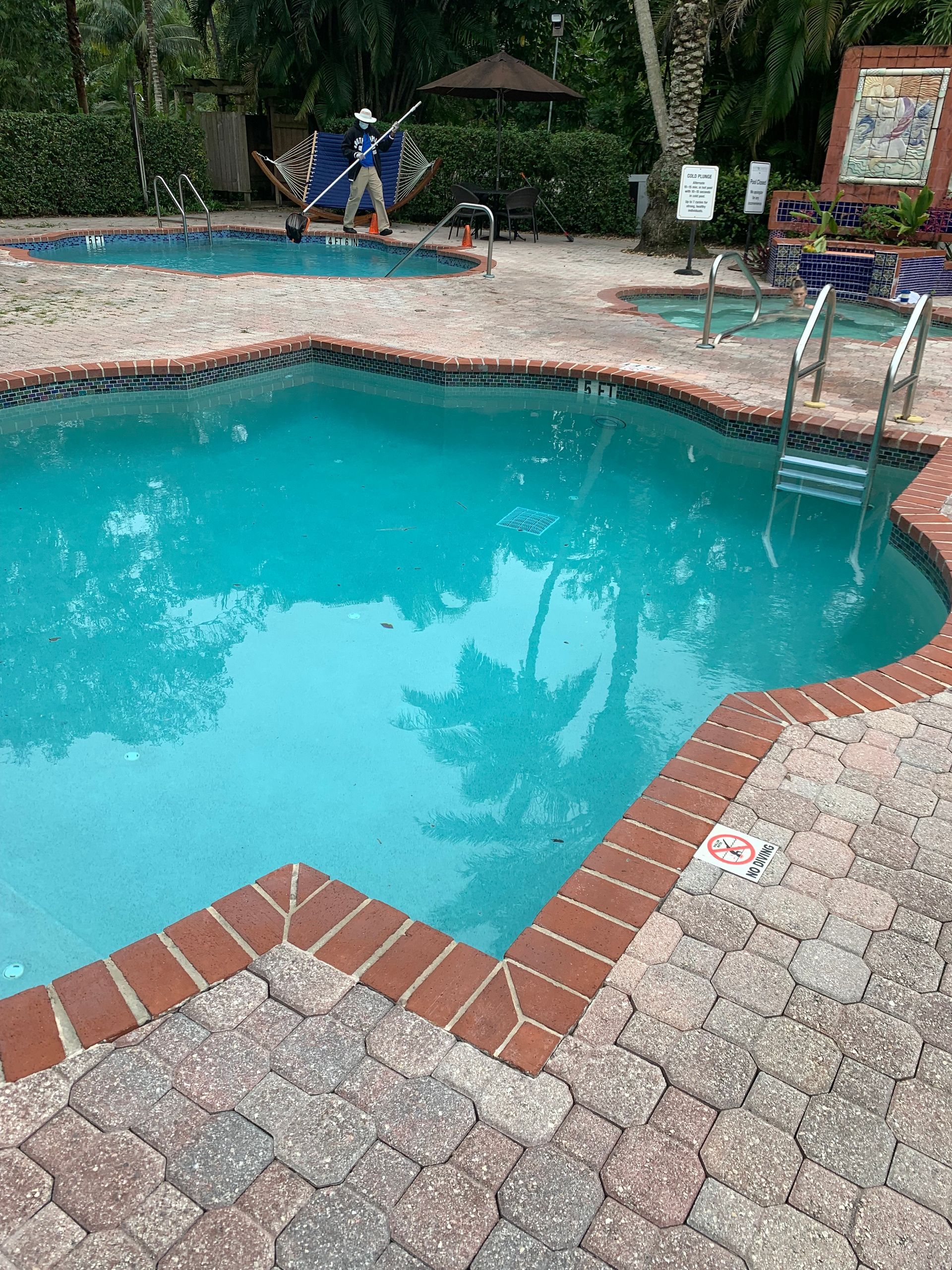 Backyard pool with turquoise water and brick coping, surrounded by stone patio and lounge chairs