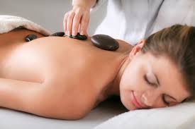 Person receiving a hot stone massage while lying face down on a treatment table