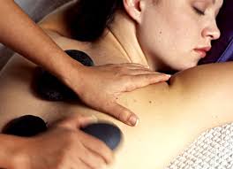 Person receiving a back massage with massage stones placed on the skin
