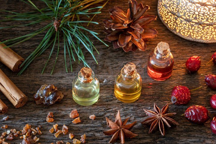 Aromatic spices and essential oil bottles arranged on a rustic wooden table with pine sprigs and star anise
