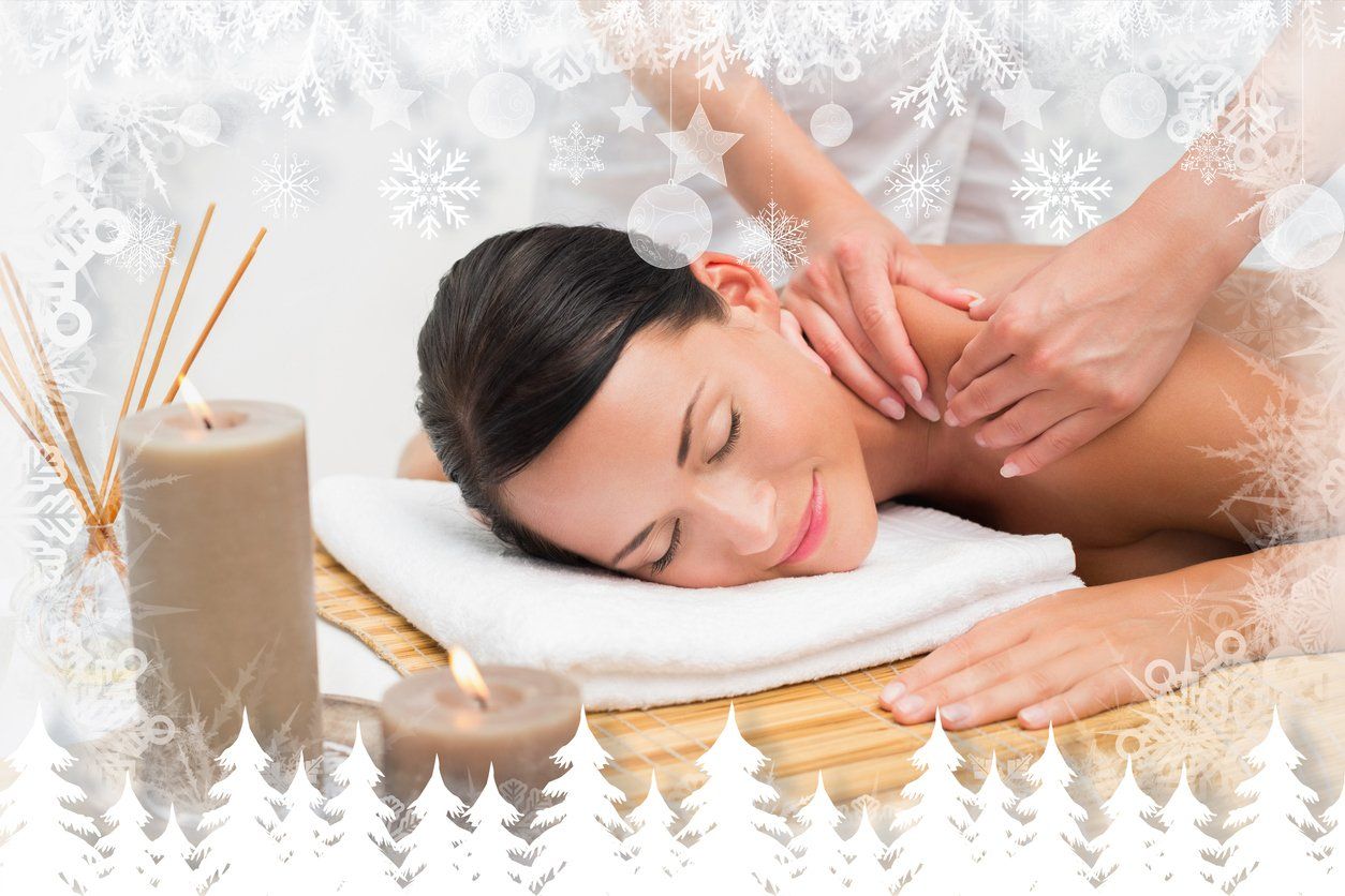 Woman receiving a relaxing spa massage, resting face down on a towel with candles nearby