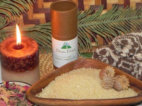 Candle, pine sprigs, round tin, and bowl of grains arranged on a rustic table.