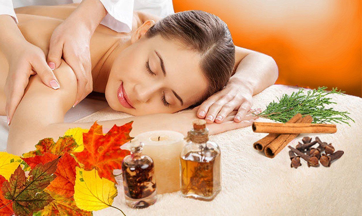 Person lying on a spa table with green towels and white flowers, in a relaxing massage setting