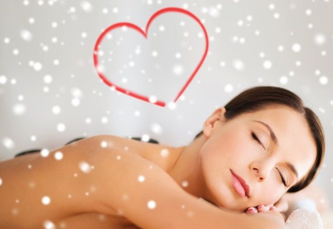 Woman relaxing with eyes closed, resting on a white towel, with a red heart and soft white bubbles in the background