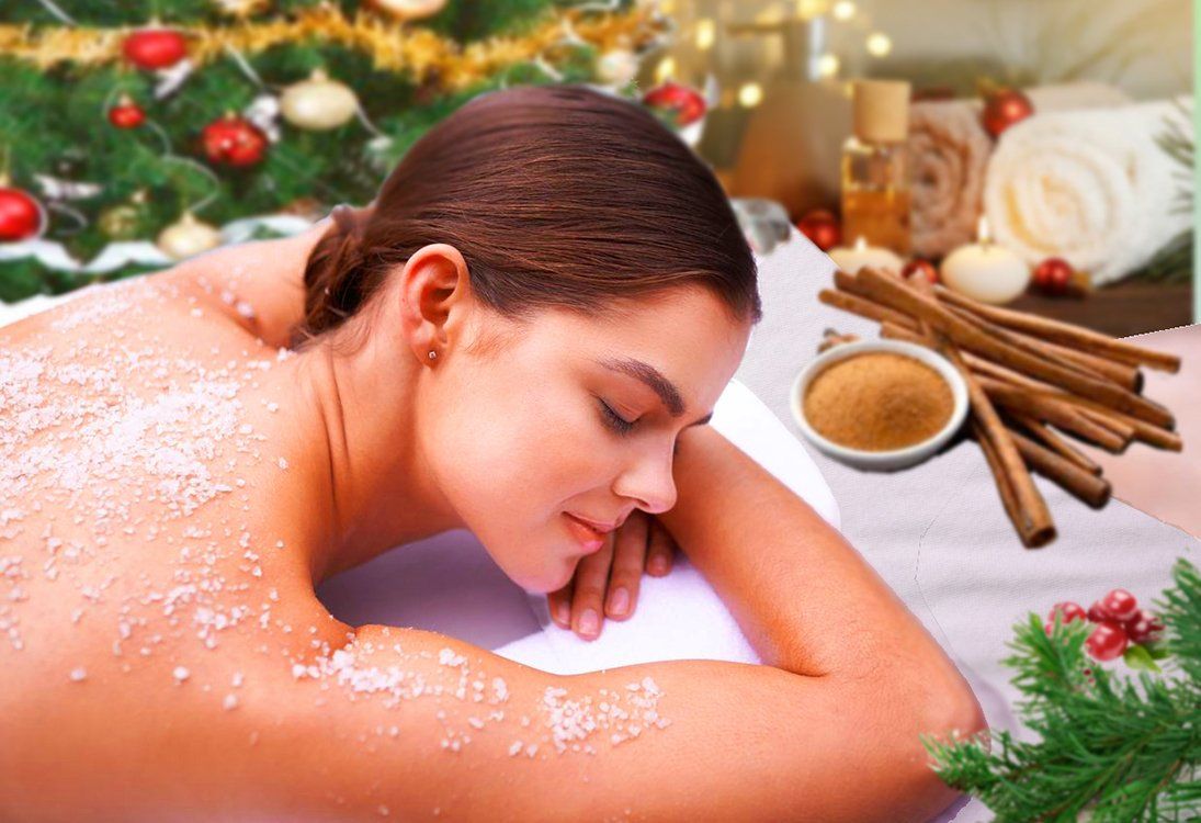 Woman relaxing with eyes closed during a spa massage, surrounded by flowers, candles, and cinnamon sticks