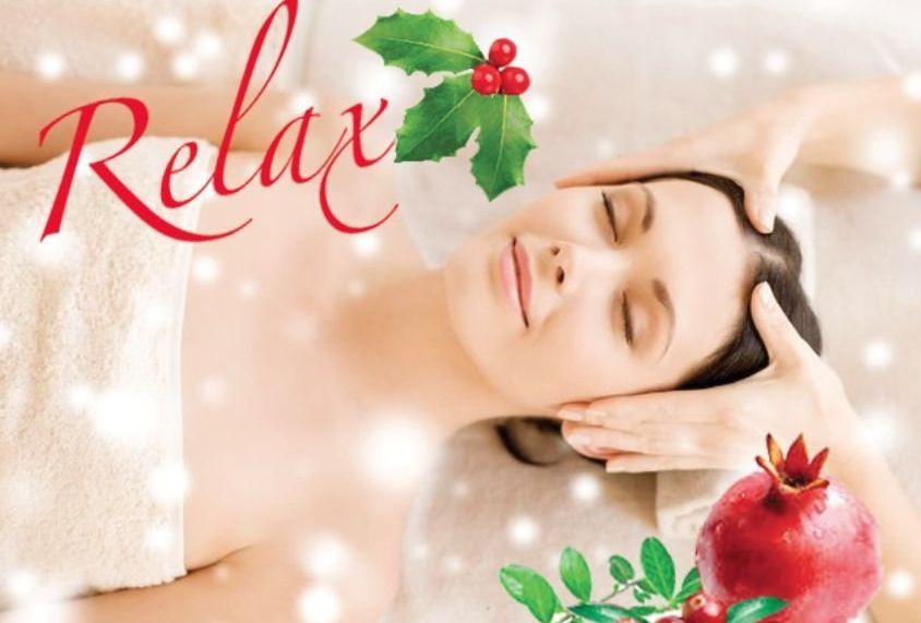 Relaxing woman with eyes closed during a spa bath, with holly and pomegranate accents