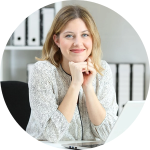Woman at desk, smiling, resting chin on hands, in office with laptop and files.