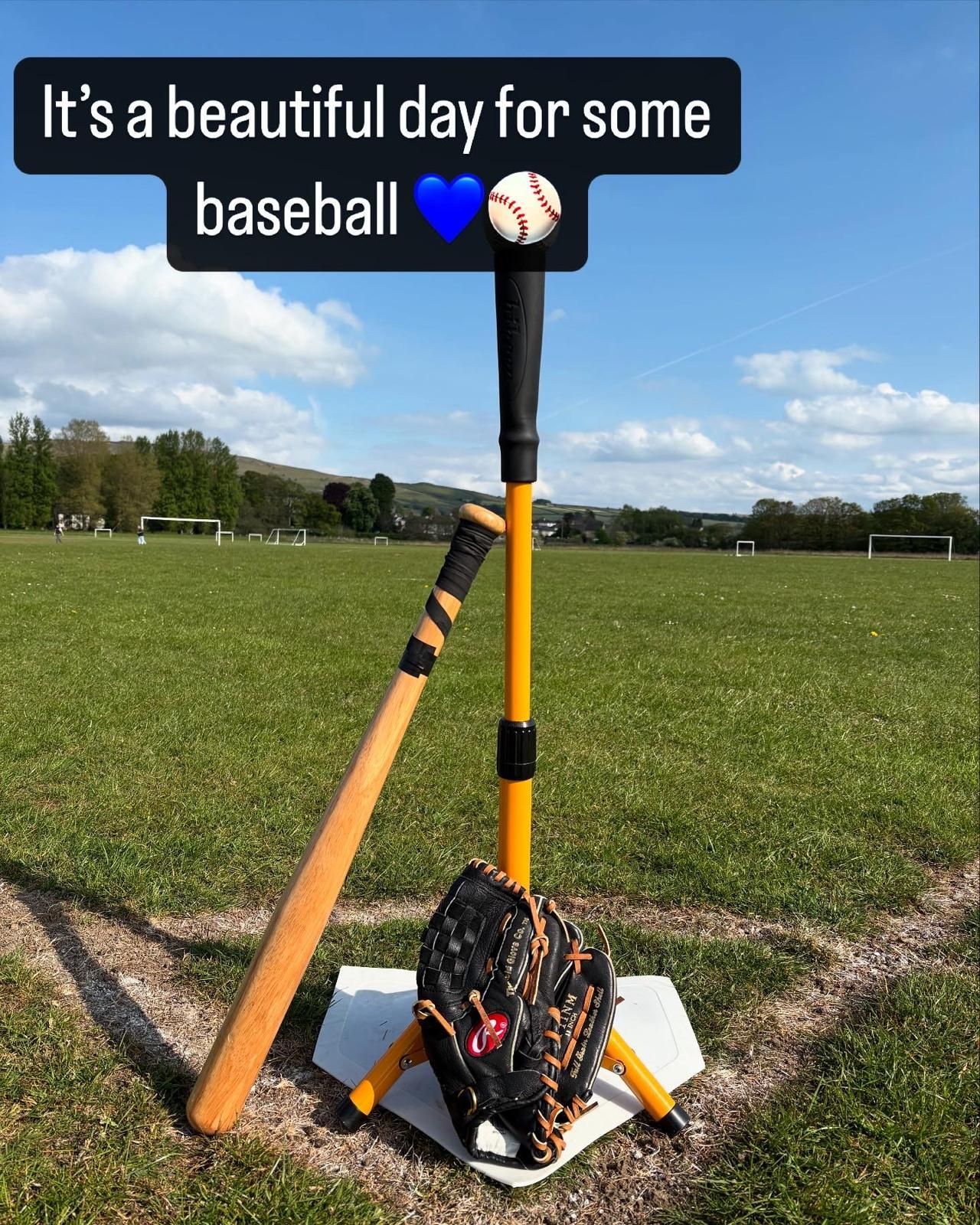 Baseball setup on a field: tee, bat, glove, ball. White home plate, blue sky. Text: 