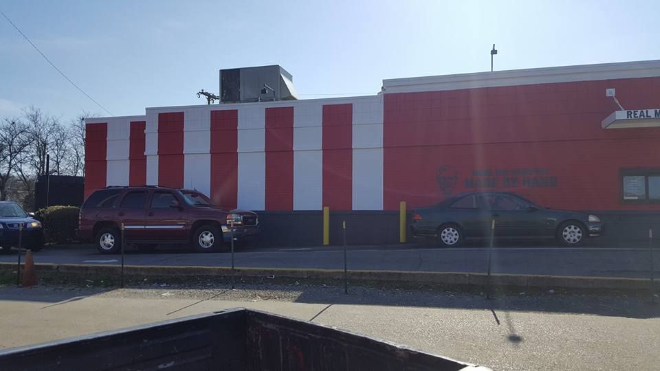 Red and white striped building with cars parked in front on a sunny day.