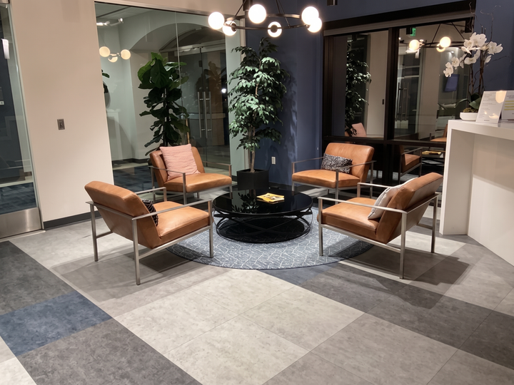 Modern lounge with gray sofas, white tables, black chairs, and geometric floor patterns under ceiling lights