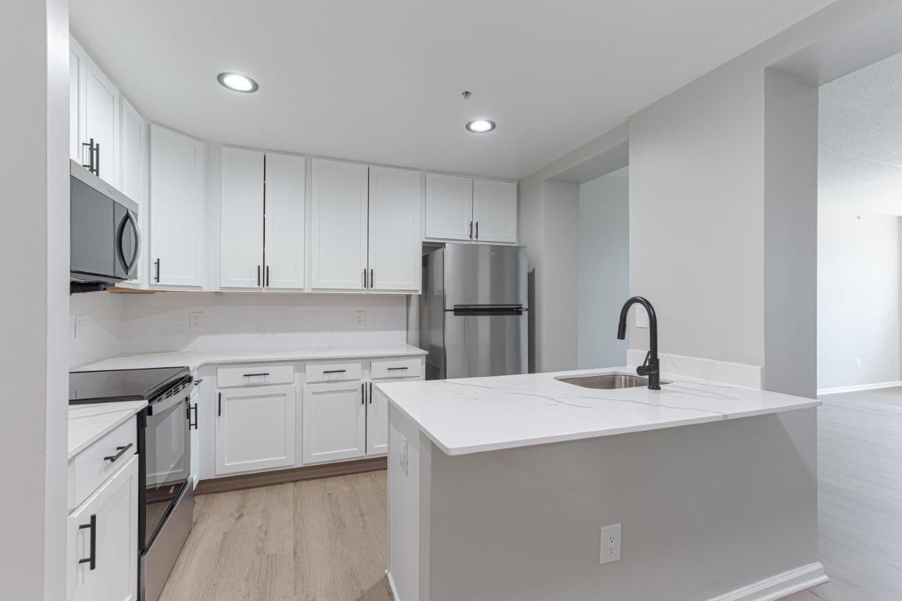 Bright modern white kitchen with stainless steel appliances and a central island with sink