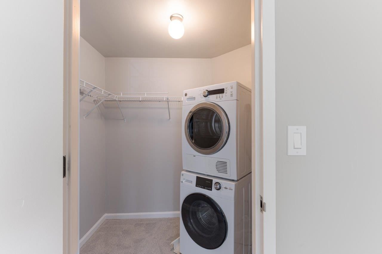 Walk in closet with stacked washer and dryer, wire shelving, and white walls