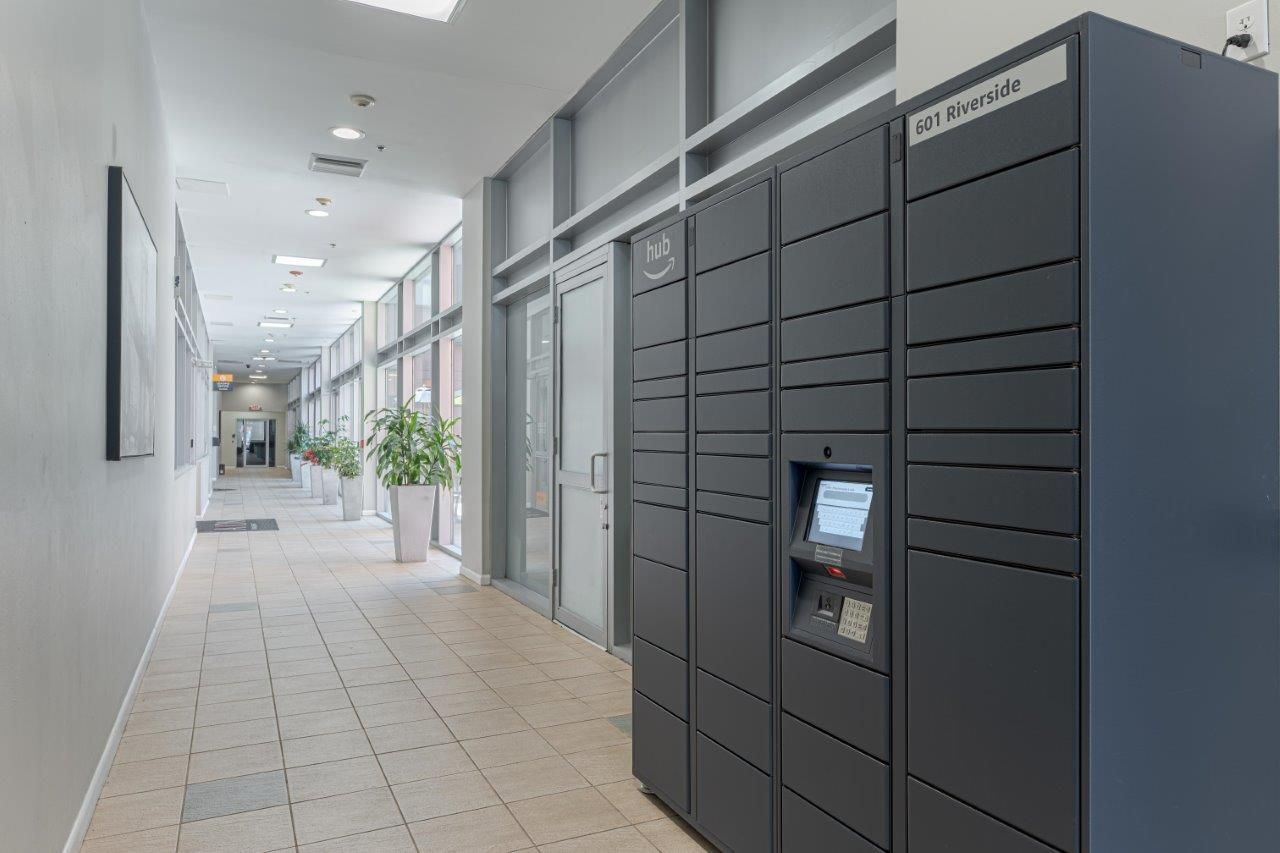 hallway with dark gray package lockers on the right and large windows on the left