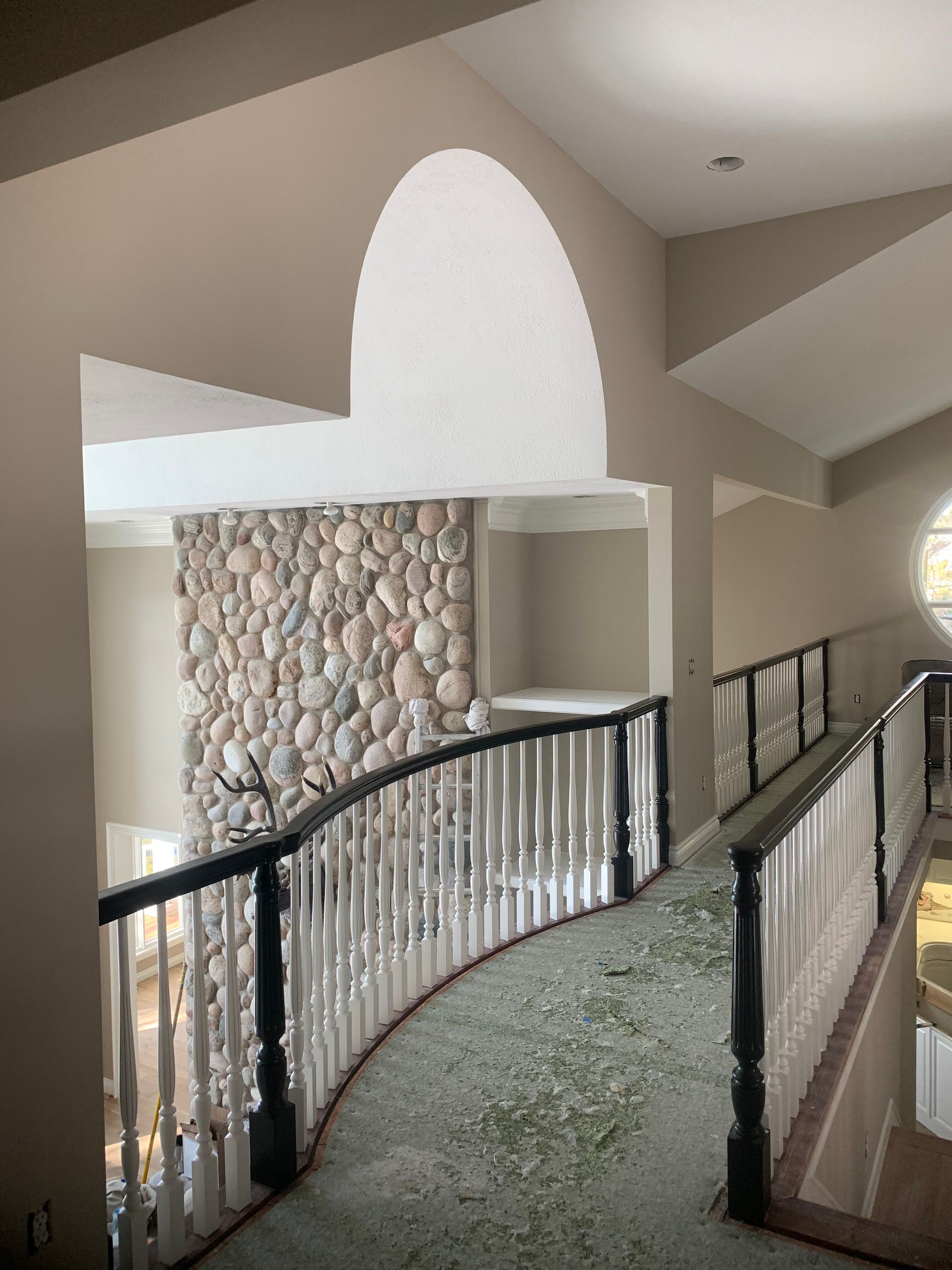 Hallway with curved railing, stone fireplace, and arched ceiling.
