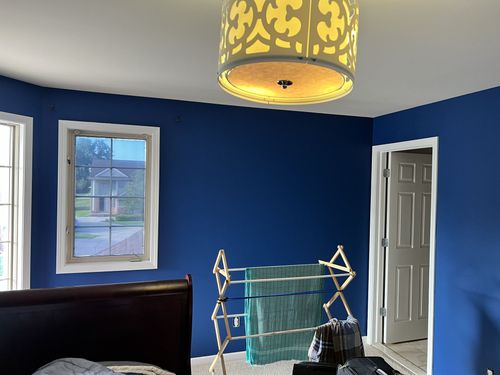 Bedroom with blue walls, a drying rack with turquoise towels, and a decorative ceiling light.