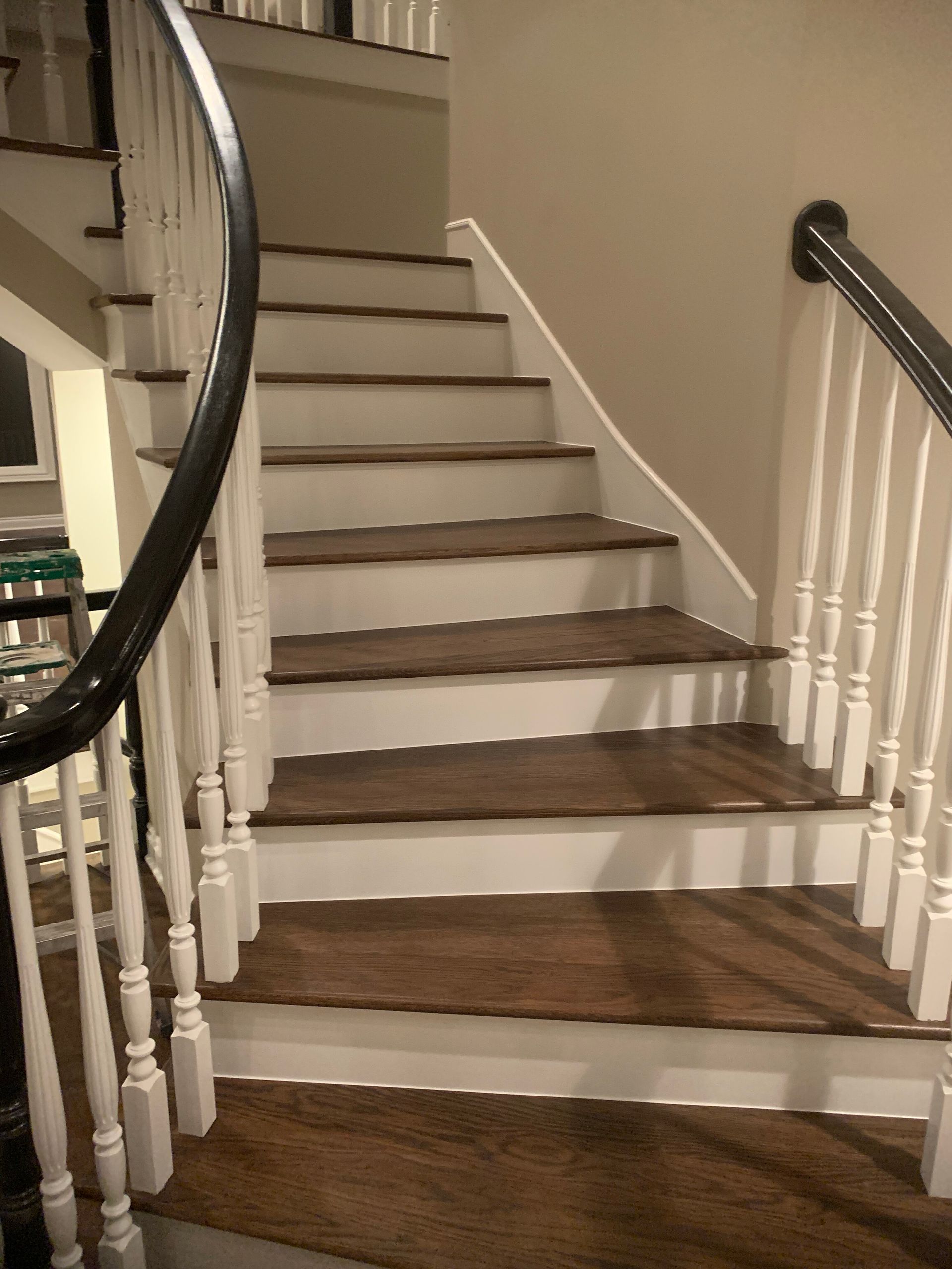 Staircase with dark wood treads, white risers and spindles, and a curved dark railing.