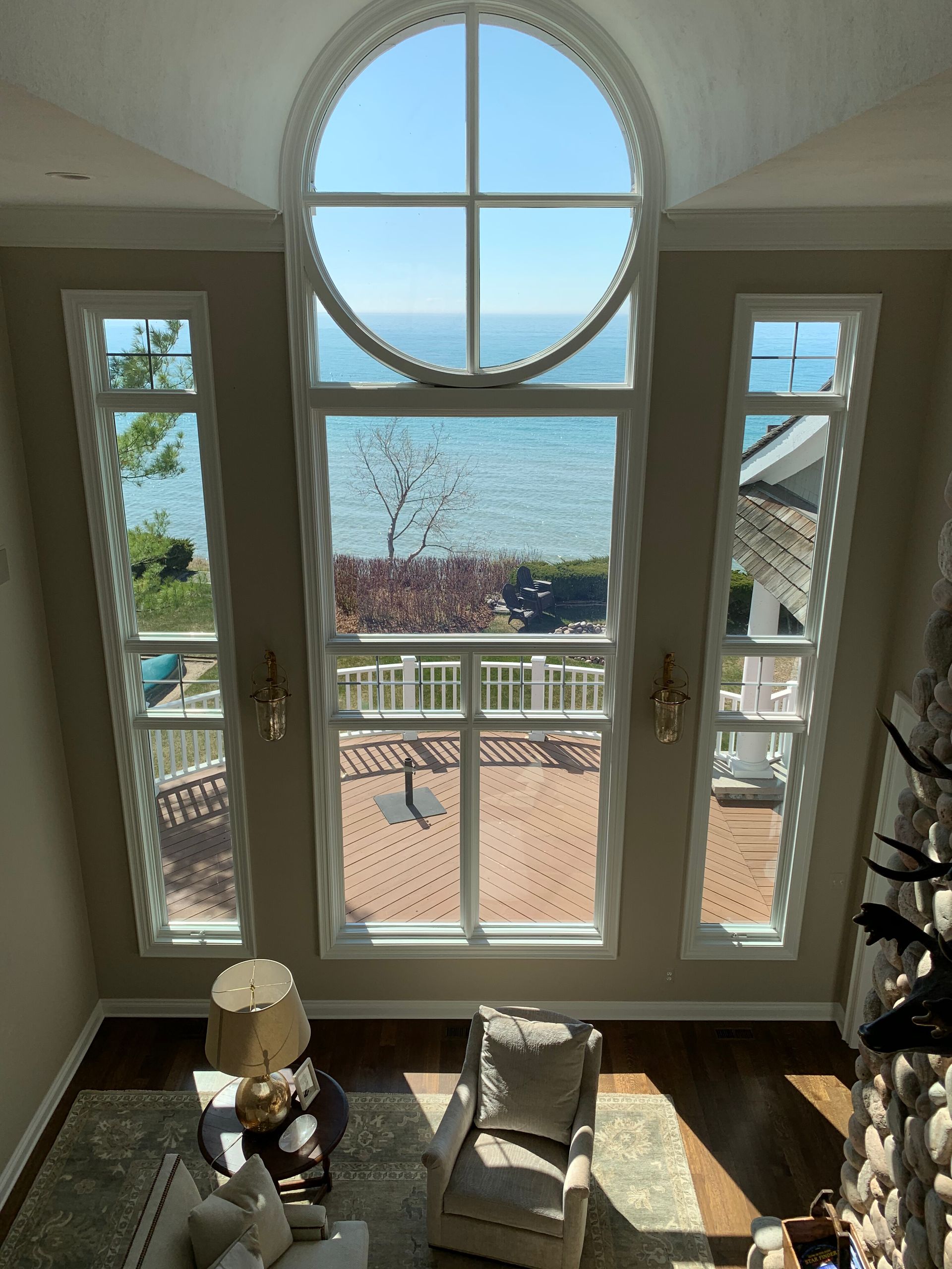High-angle view of large windows overlooking a lake. A living room with seating below.