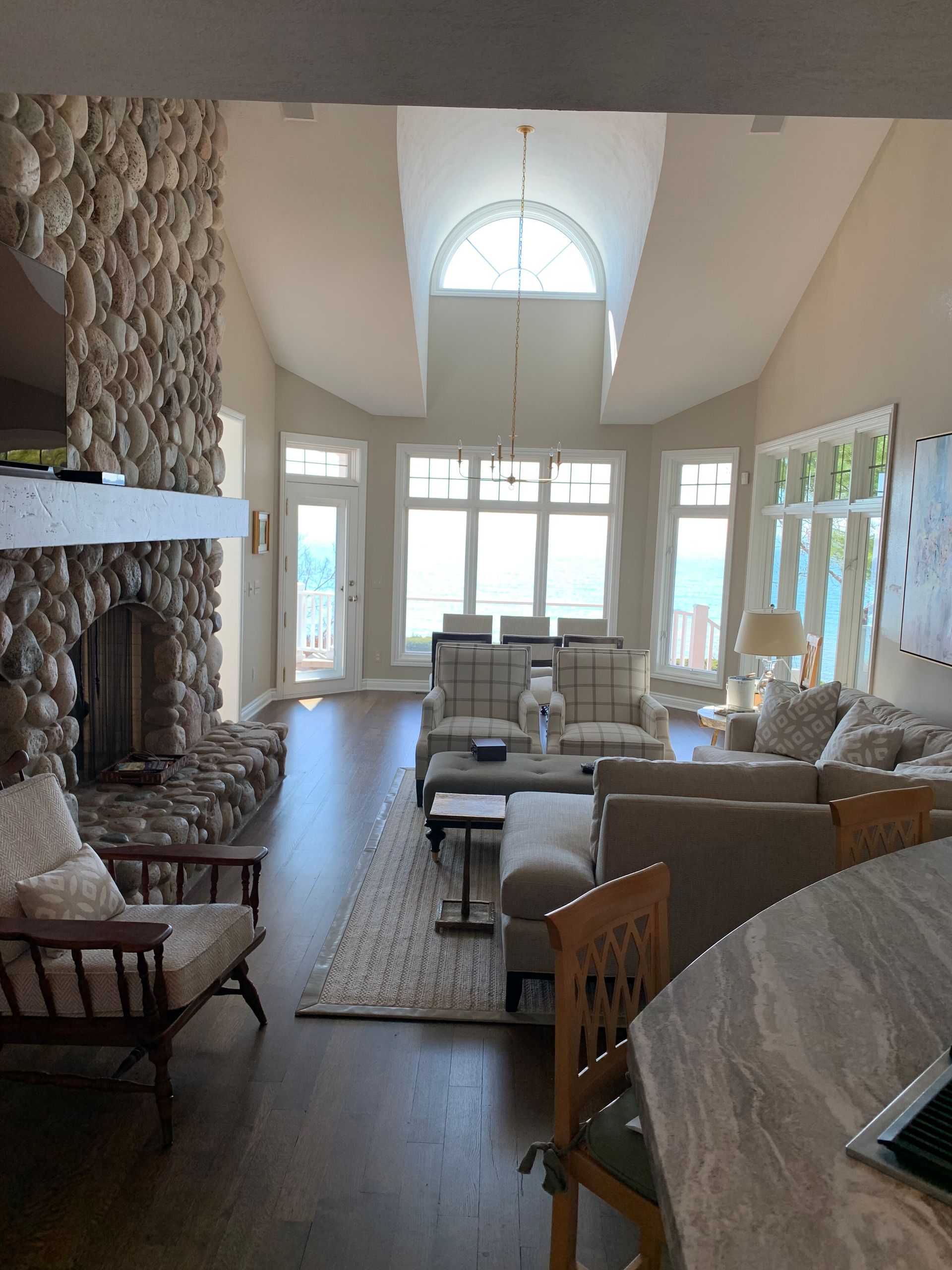 Spacious living room with stone fireplace, large windows, and neutral-toned furniture.