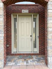 Beige front door with sidelights, brick archway, and address number 4123.