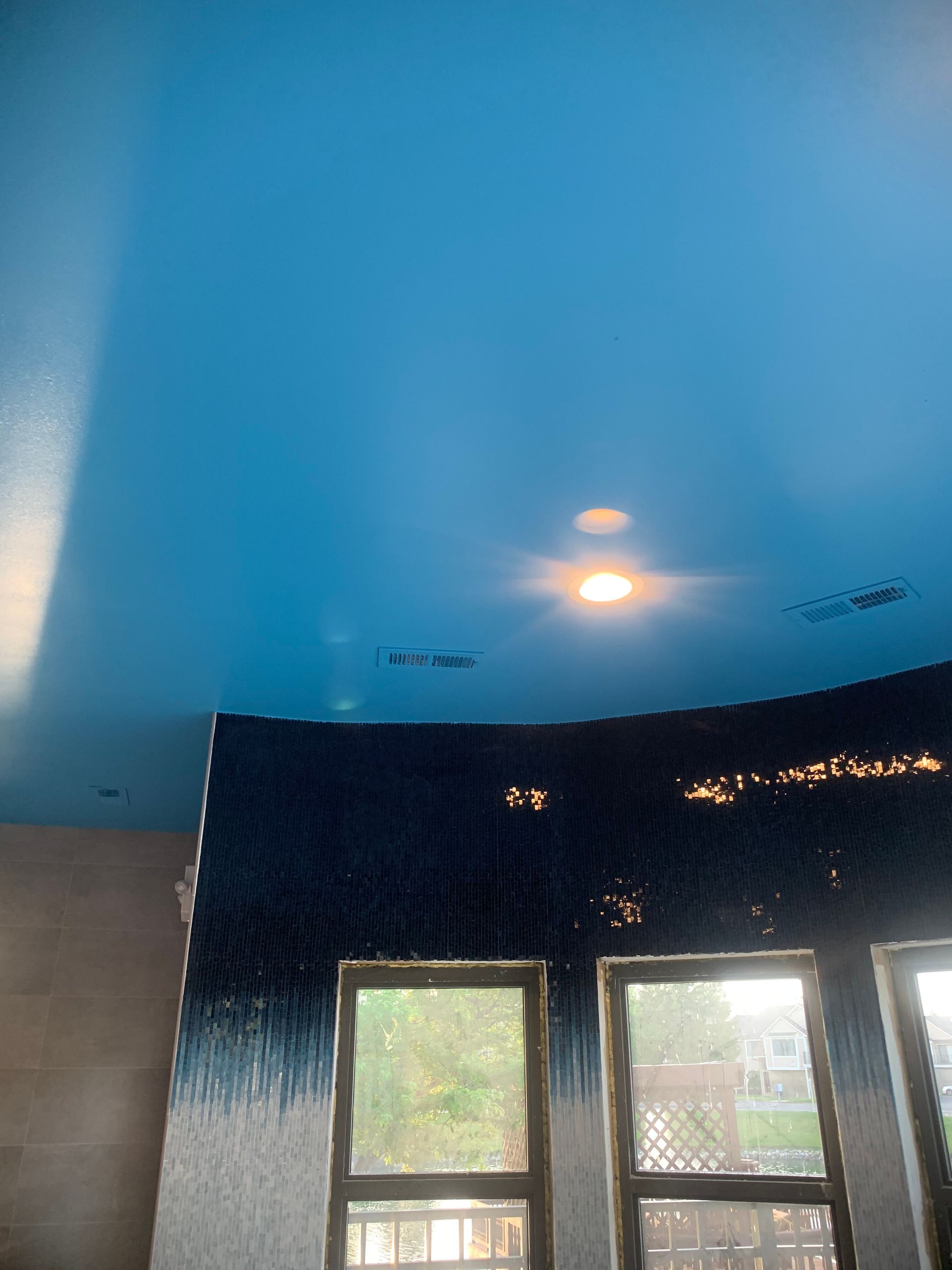 Blue ceiling with light fixtures, arched wall with dark blue-white gradient, and windows.