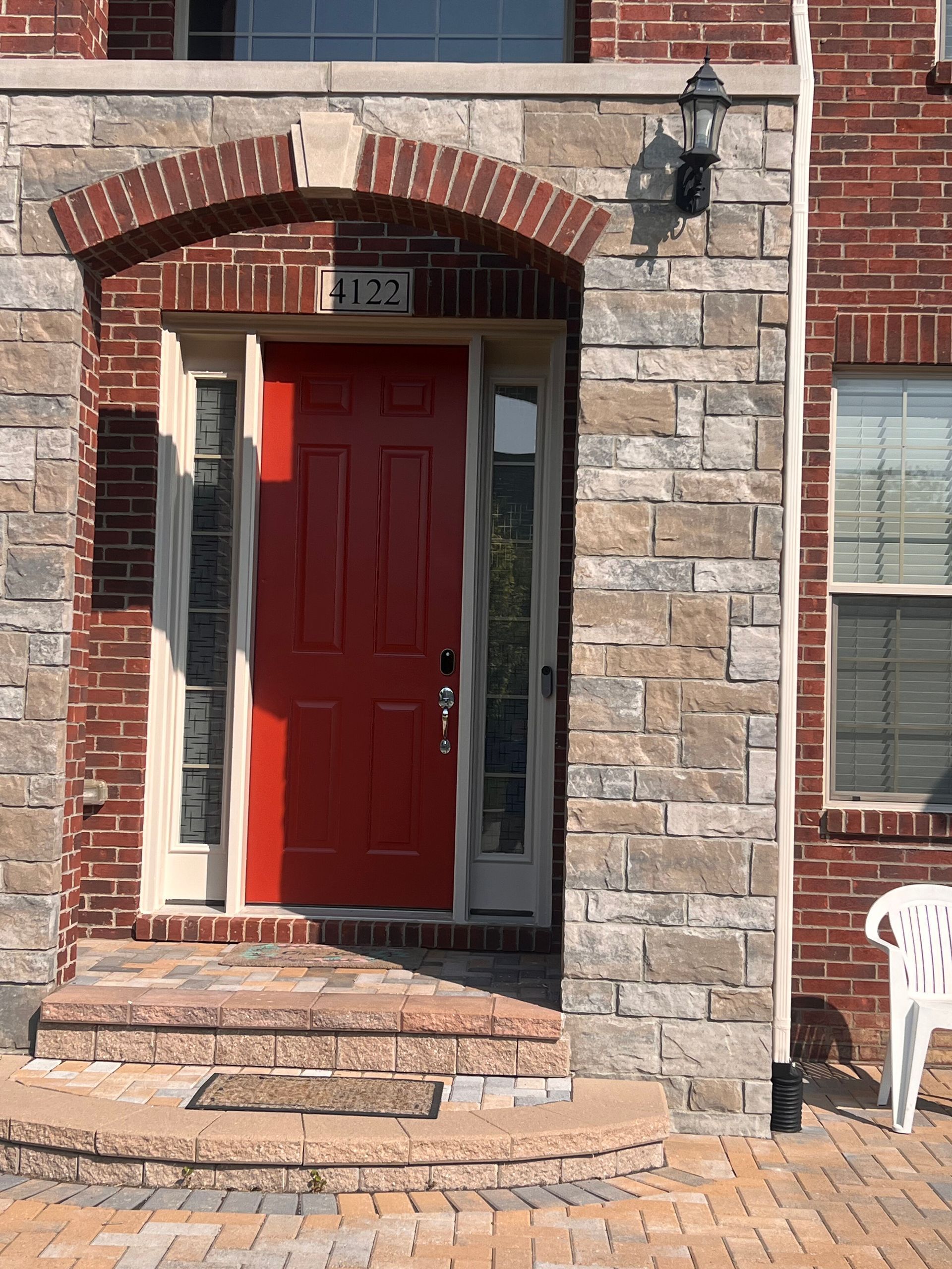 Red front door under a brick archway and stone facade with steps.