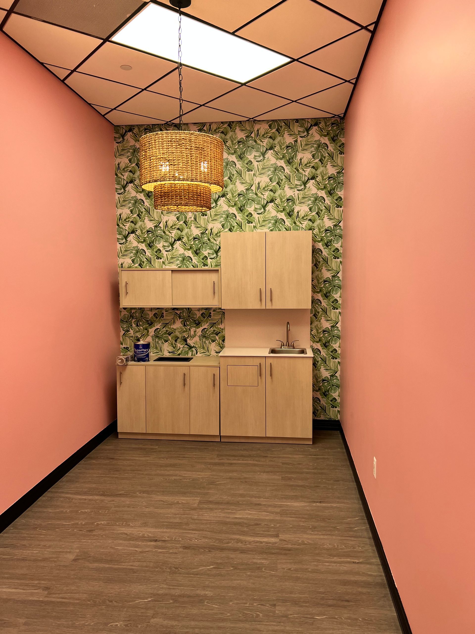 Pink-walled room with wooden cabinets against a green patterned wall; gold light fixture on wall.