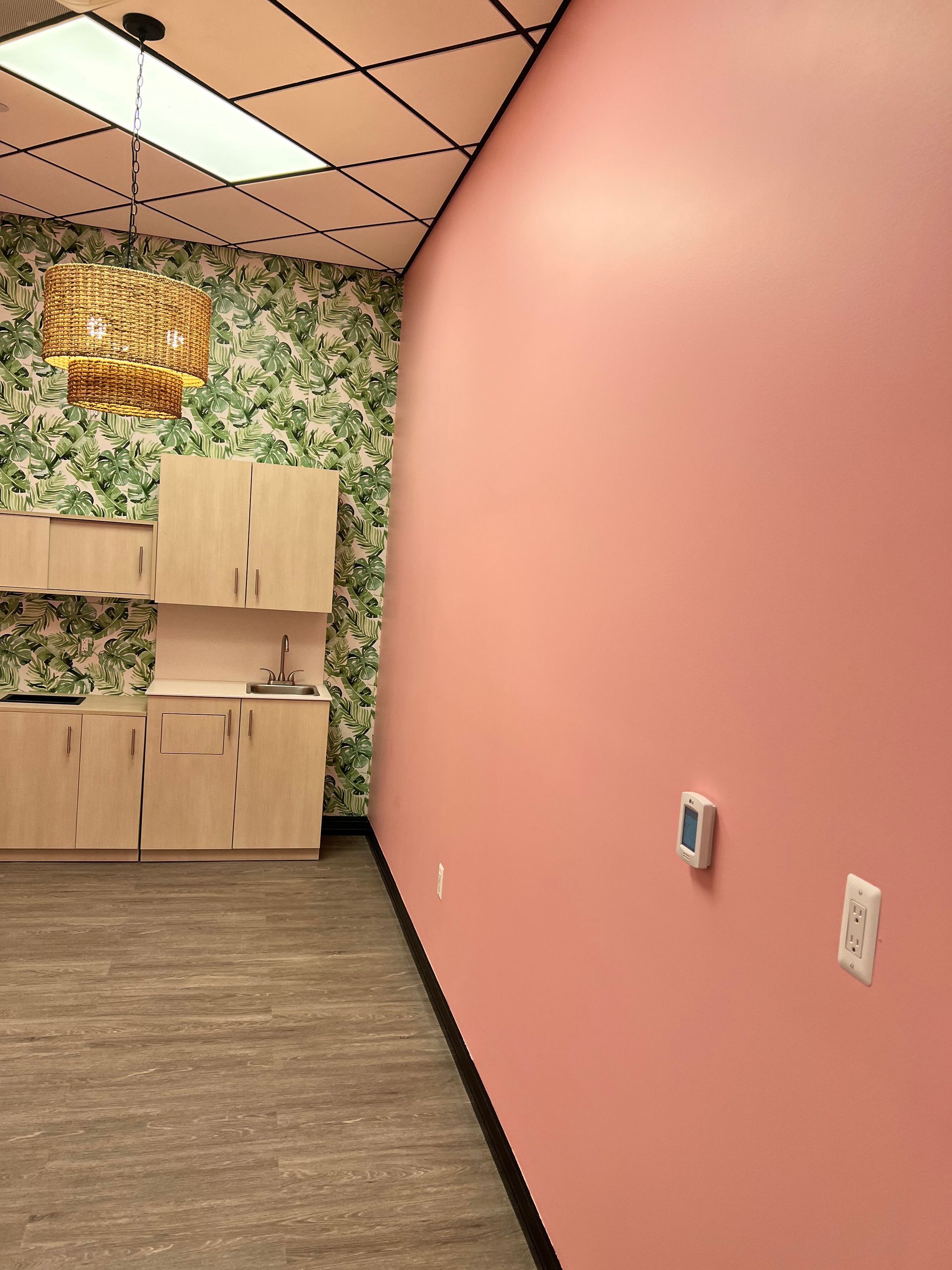 Pink wall in an office space with a patterned wallpaper wall and cabinets.