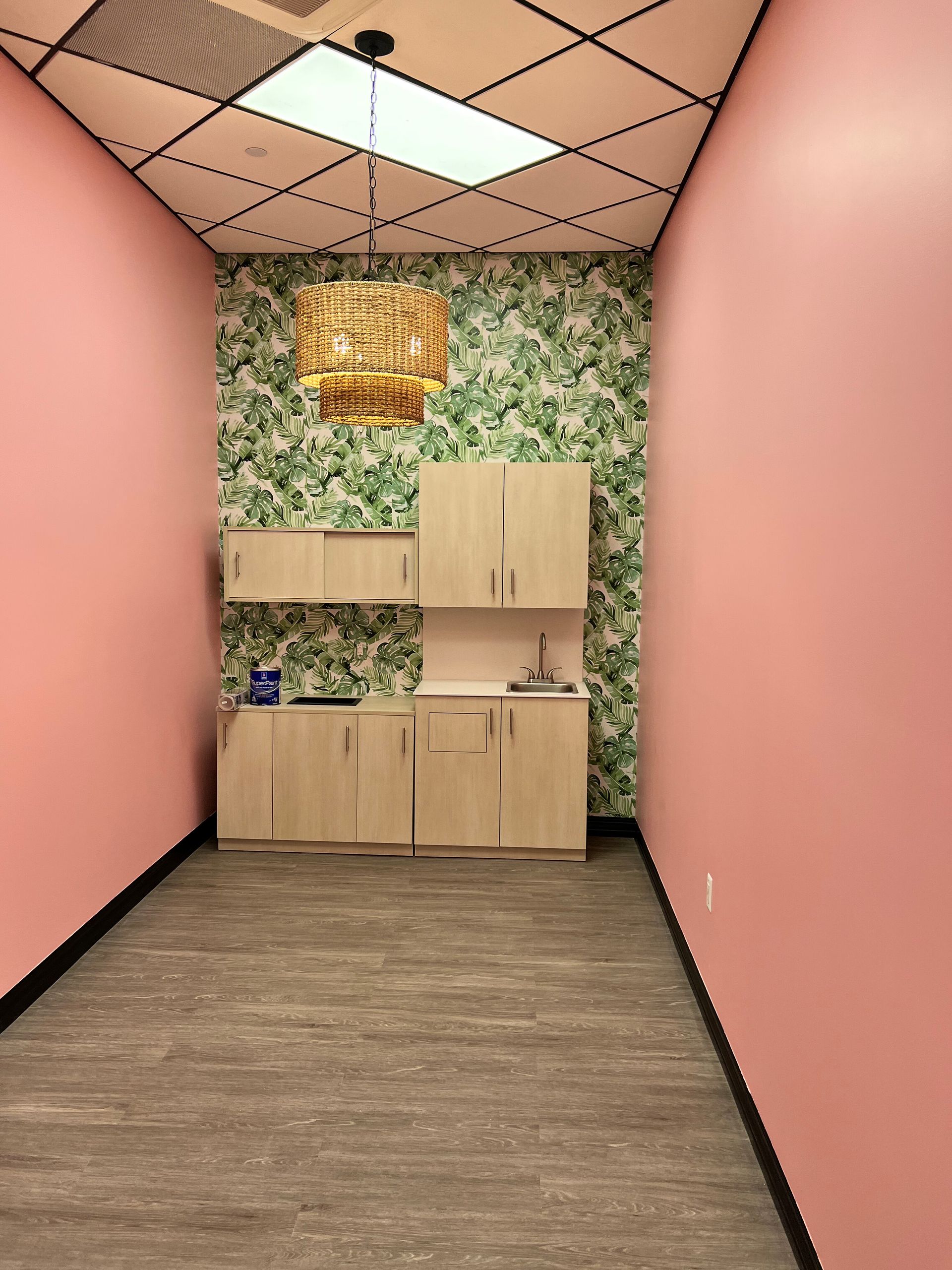 Small room with pink walls, wood cabinets, and green floral wallpaper.