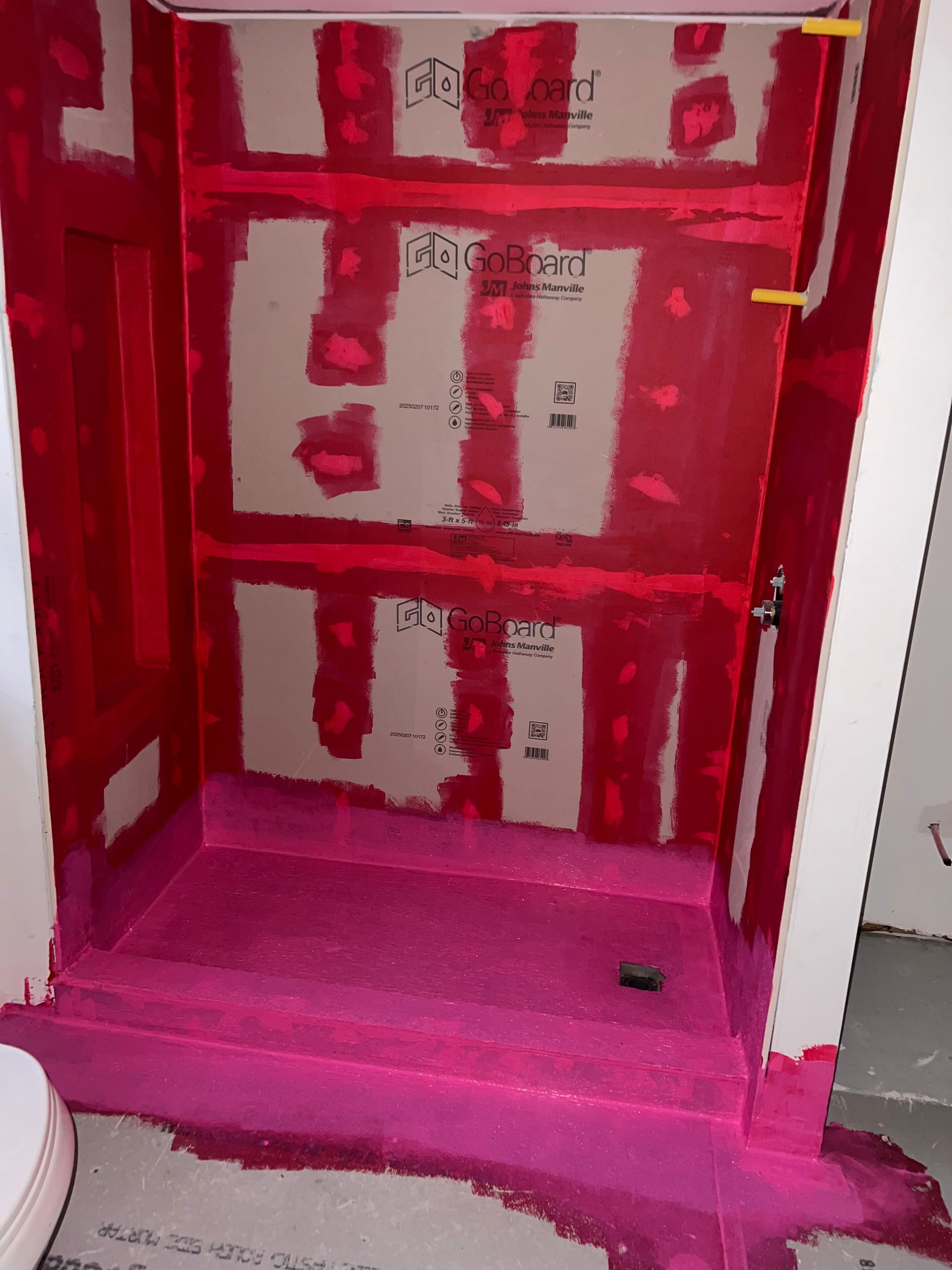 Shower stall under construction, coated with bright pink sealant.