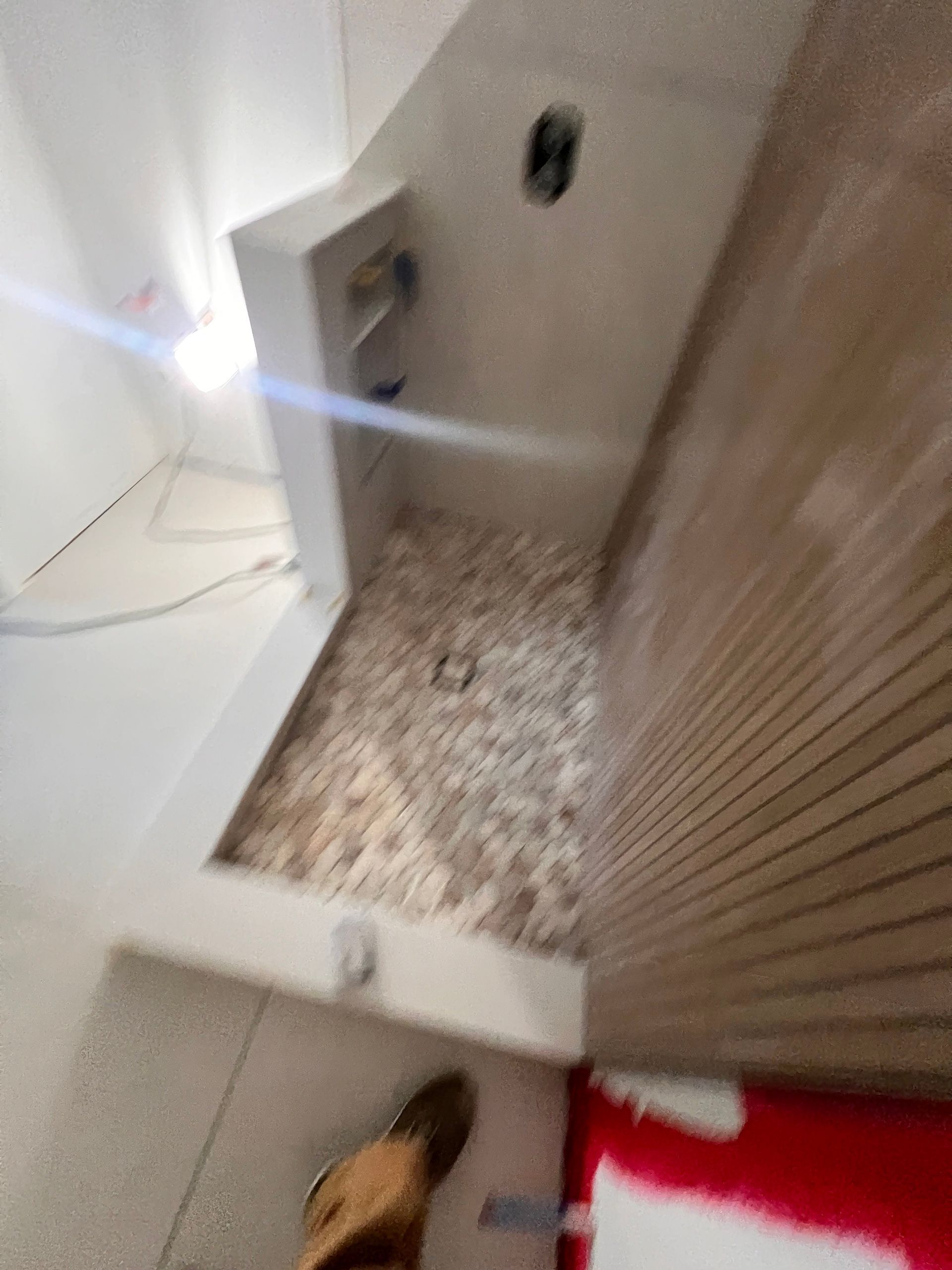 Shower stall with stone floor and tan ribbed wall.