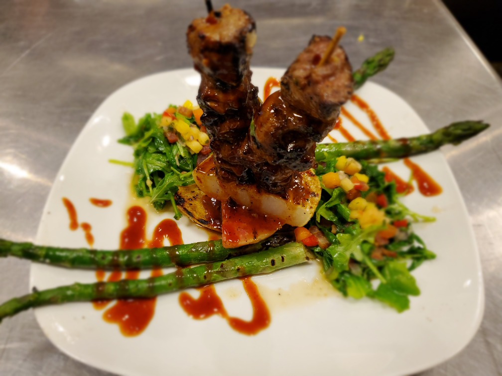 A white plate topped with meat and asparagus on a table.