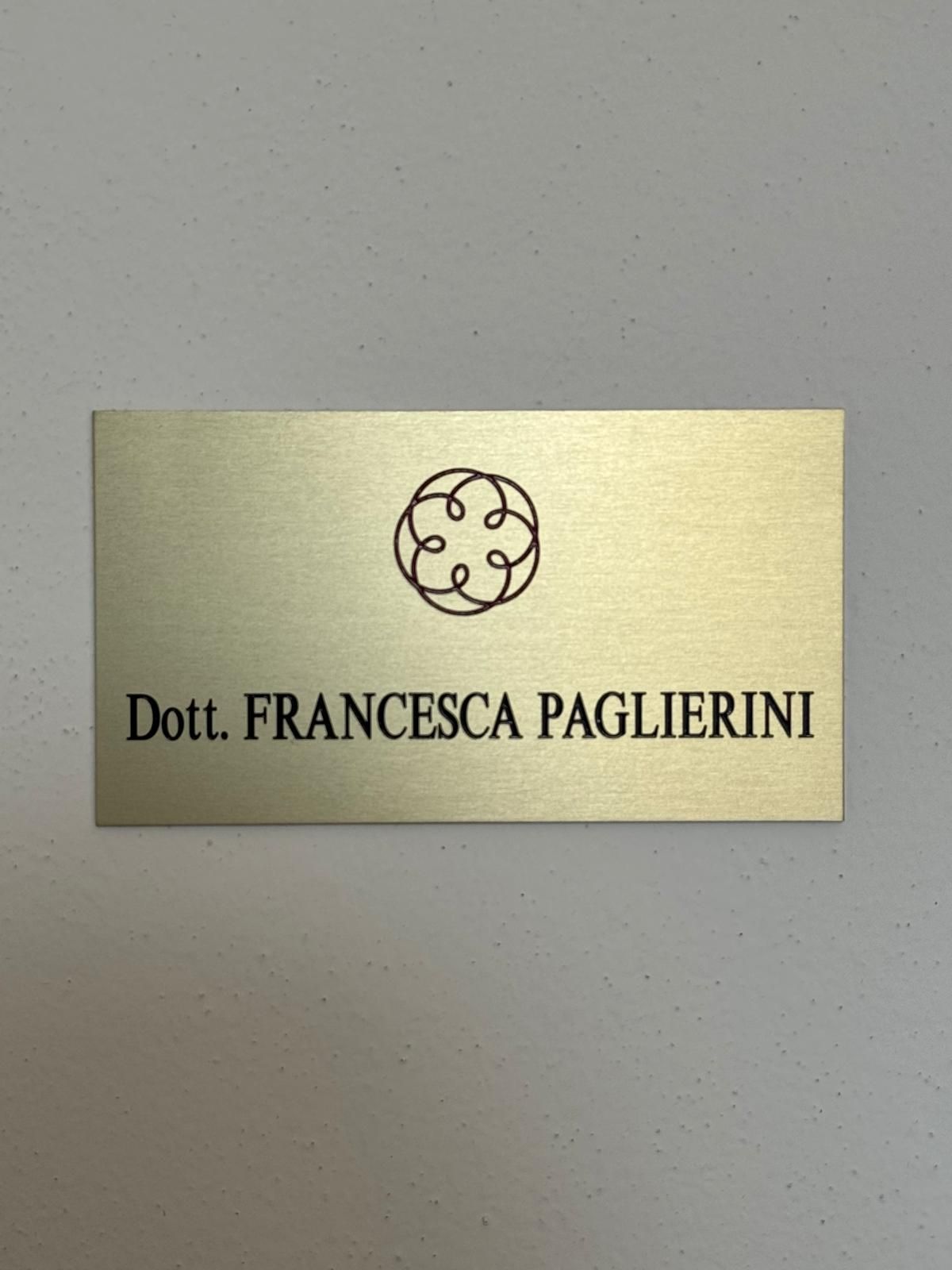 Targhetta dorata sulla parete con la scritta “Dott. Francesca Paglierini” e un logo circolare sopra.