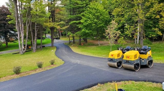 Two asphalt rollers are sitting on the side of a road.