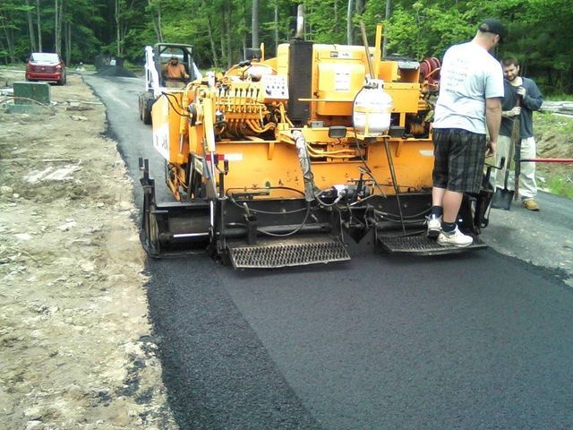 A man standing next to a machine that says ' asphalt ' on it