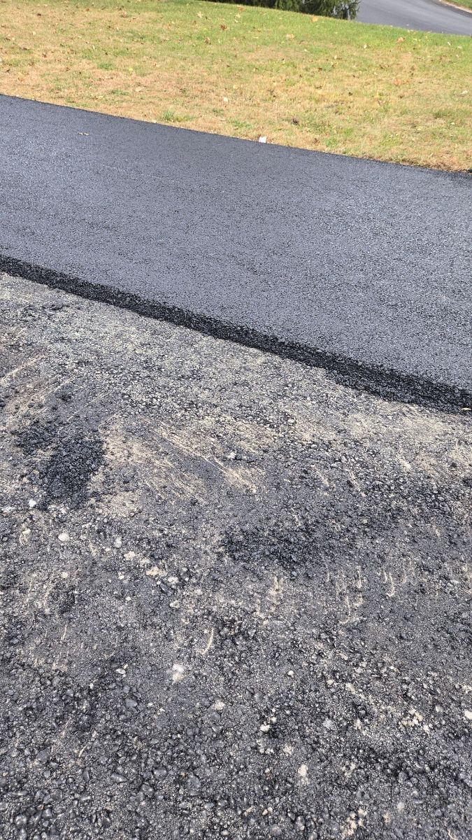 Newly paved black asphalt path next to a rough, older asphalt surface.