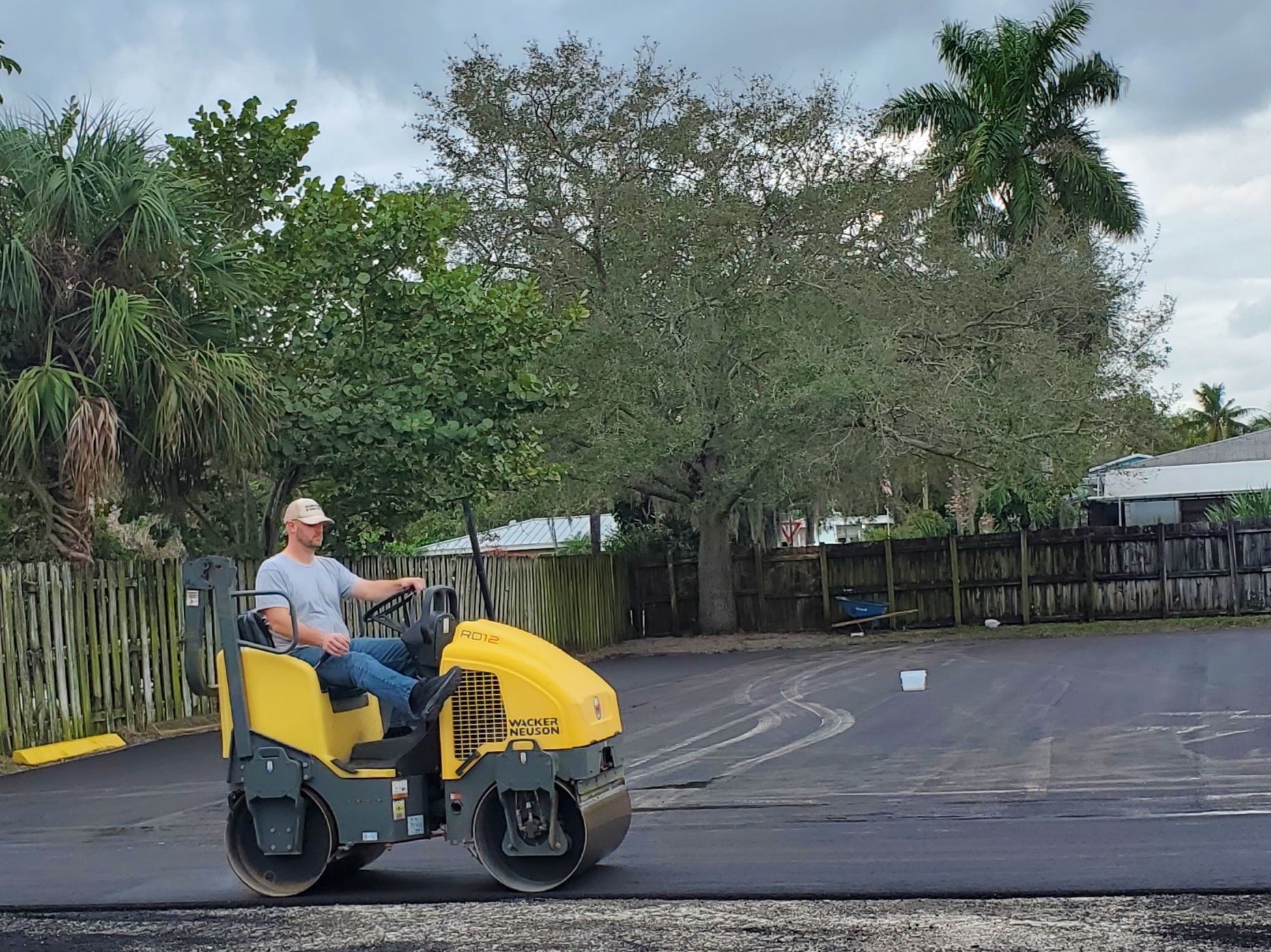 A man is driving a yellow roller on a road.
