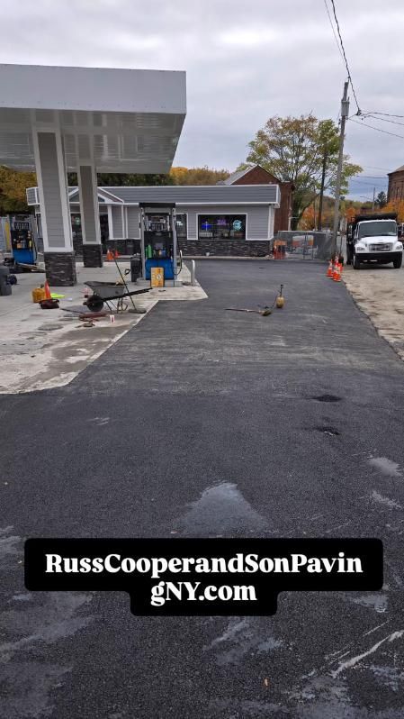Newly paved gas station with canopy, pumps, and convenience store. Construction cones and truck.