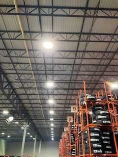 Warehouse interior with tall steel racks stacked with tires under bright ceiling lights