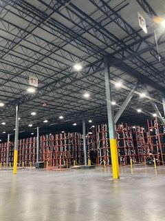 Warehouse interior with tall metal shelving, yellow columns, and a polished concrete floor