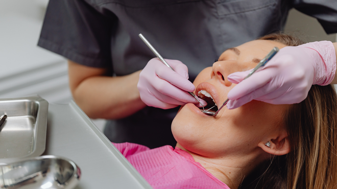 Dentist examining a patient’s teeth with gloved hands in a dental clinic