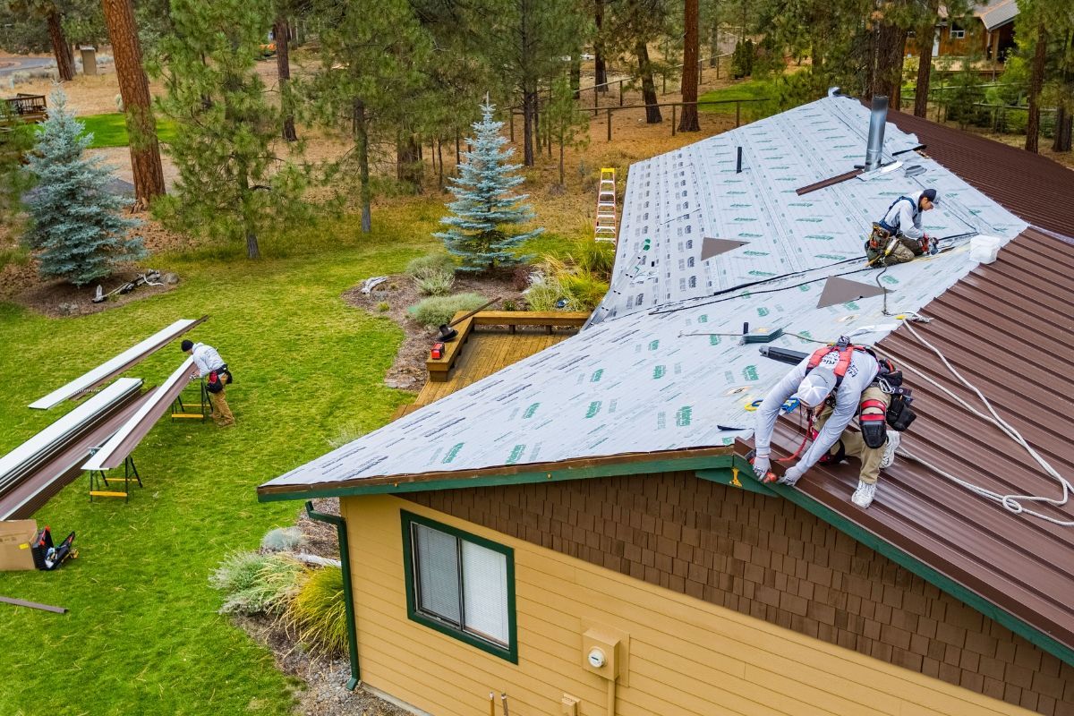 Workers repairing brown metal  roof on a house