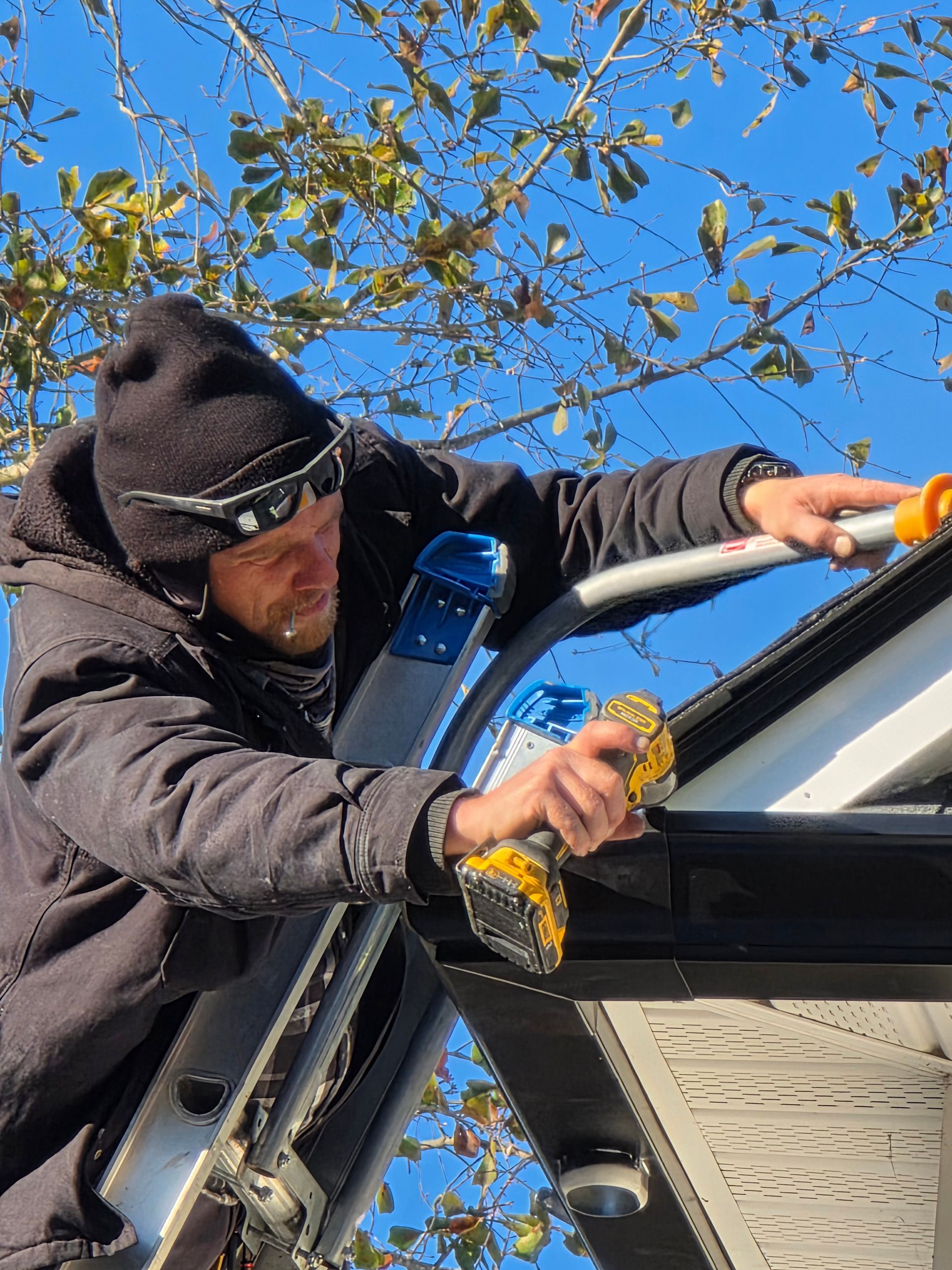 Person cleaning a car window with a squeegee outdoors under a blue sky